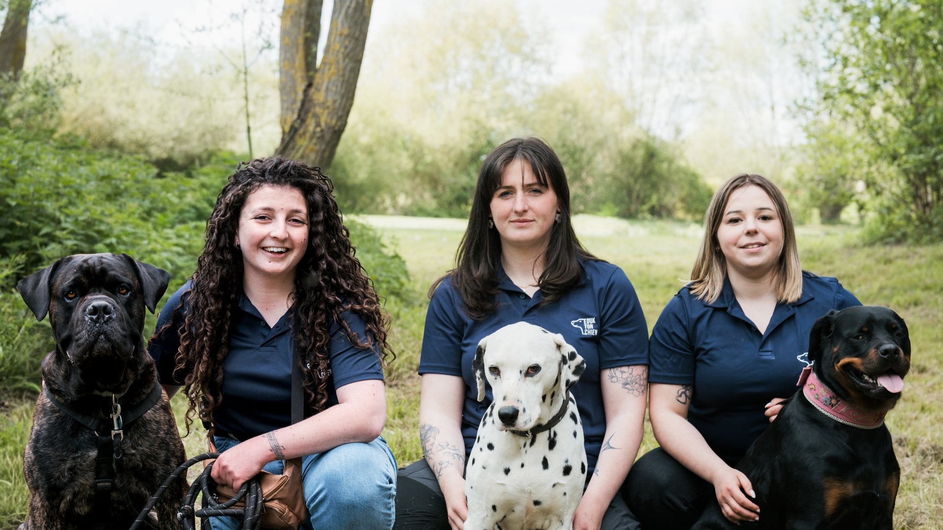 L'équipe d'Eduk ton chien, trois éducatrices canines entourées de leurs chiens en extérieur