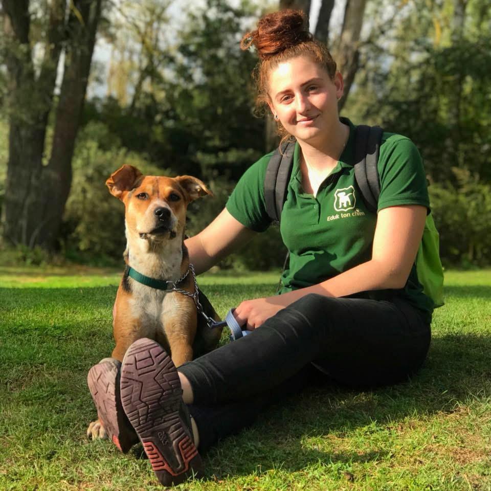 Ashley, éducatrice canine, assise dans l'herbe avec sa chienne Orchi